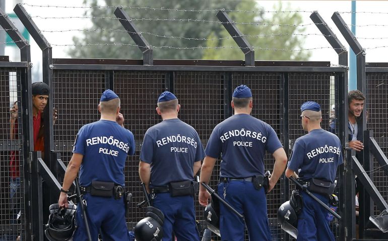 Migrants watch through the gate after Hungarian police officers closed the main border exit between Serbia and Hungary near Roszke