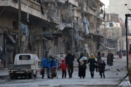 People, who evacuated the eastern districts of Aleppo, carry their belongings as they arrive in a government held area of Aleppo