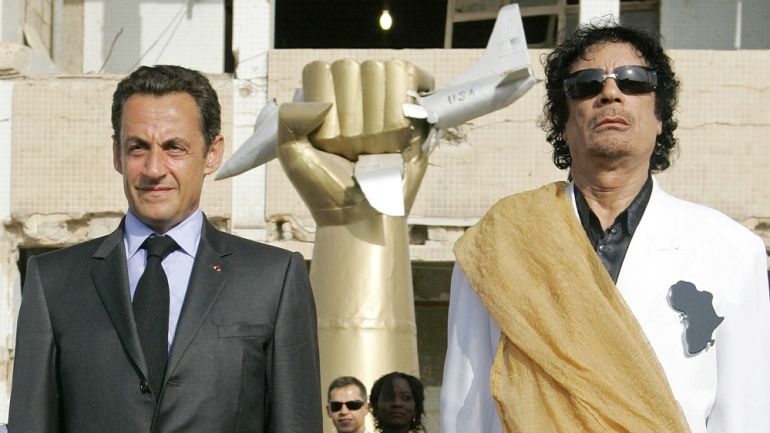 Libyan leader Muammar Gaddafi, right, and French President Nicolas Sarkozy stand while national anthems are played
