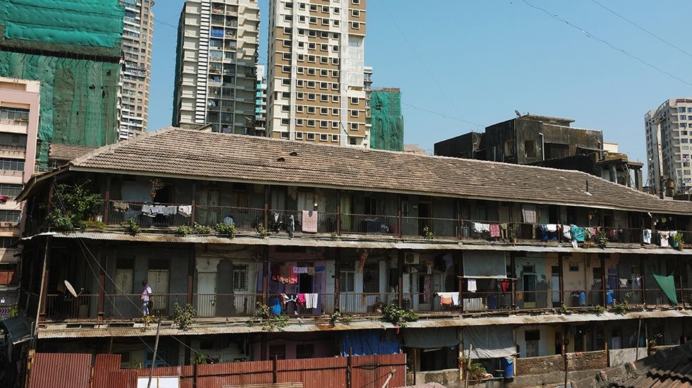 The 120-year-old Kranti Nagar chawl against the backdrop of multi-storey apartment complexes [Priyanka Borpujari/Al Jazeera] [Al Jazeera]