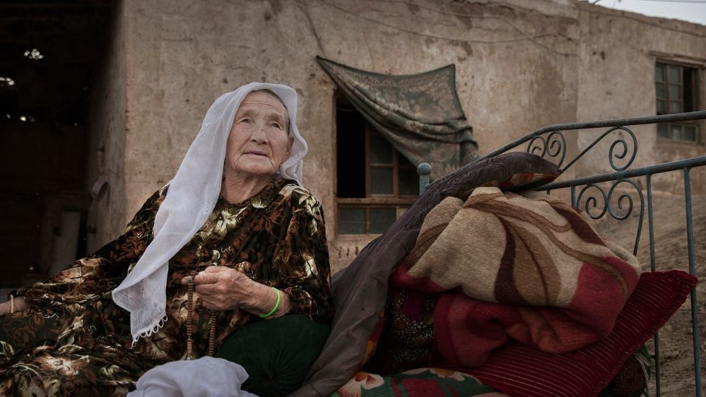A Uighur woman sits outside waiting for relatives to arrive for a holiday meal in far western Xinjiang where hundreds of thousands have been sent to detention camps that China says are skills training centres