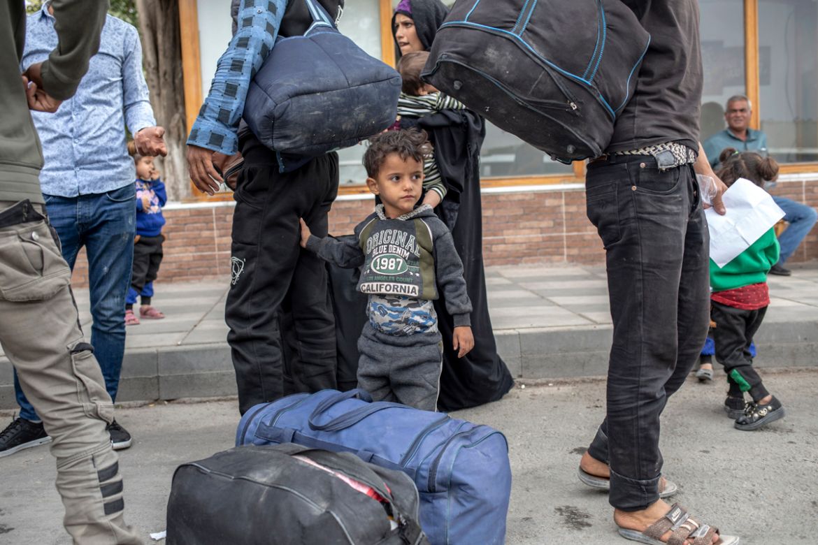 A boy stand by his father as they wait to board buses driving them back to various areas of Turkey’s Gaziantep