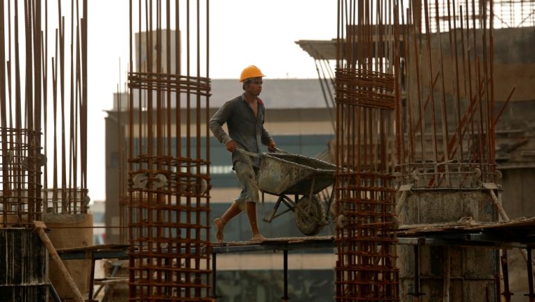 A worker pushes a wheelbarrow at a construction site in Mumbai, India, August 31, 2018