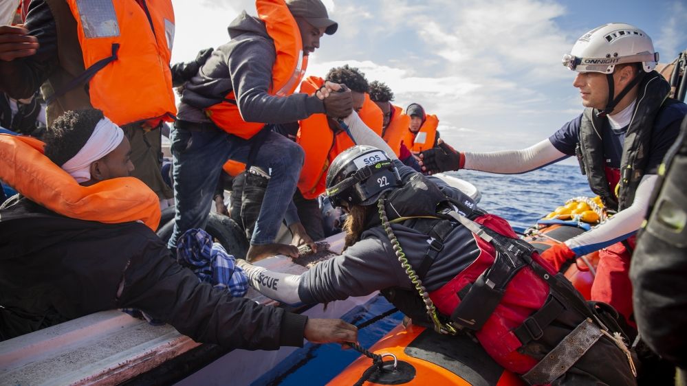 Migrants and refugees being rescued from a boat in distress in the Mediterranean