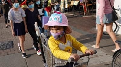 A child wearing a face mask sits on the backseat of a bicycle on Cheung Chau island near Hong Kong during Easter weekend, amid the novel coronavirus outbreak