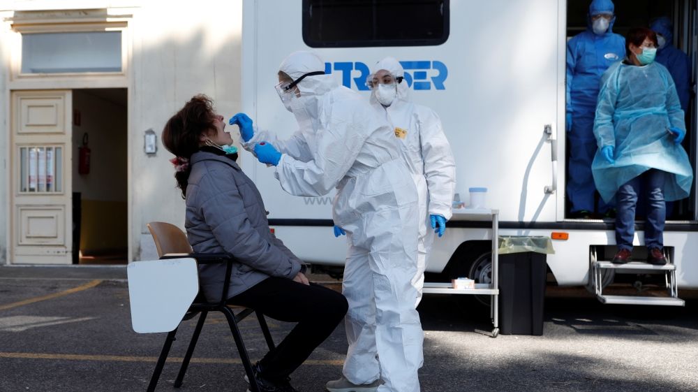A health worker wearing a protective gear swabs the mouth of a woman as the spread of coronavirus disease (COVID-19) continues, in Rome, Italy