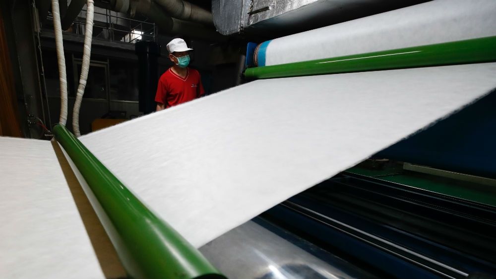 A factory worker inspects raw material for making surgical face masks in Taiwan. The island has stepped up the production of surgical face masks