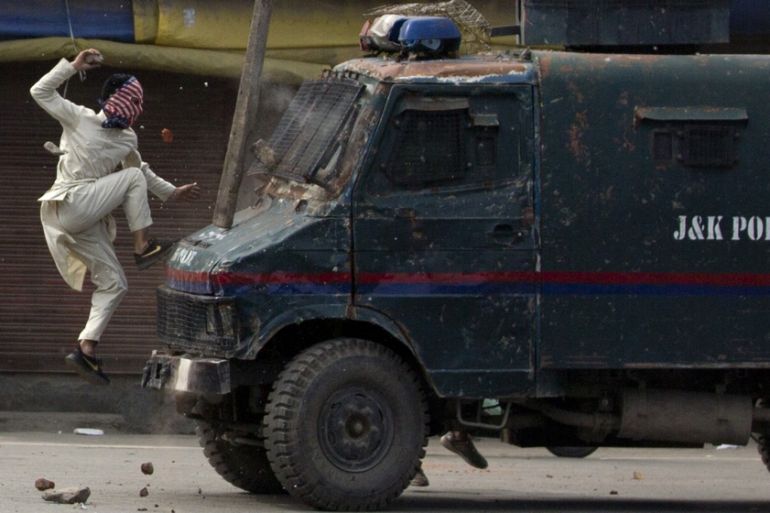 A masked Kashmiri protester jumps on the bonnet of an armored vehicle of Indian police as he throws stones at it during a protest in Srinagar, Indian controlled Kashmir, May 31, 2019. The image was pa