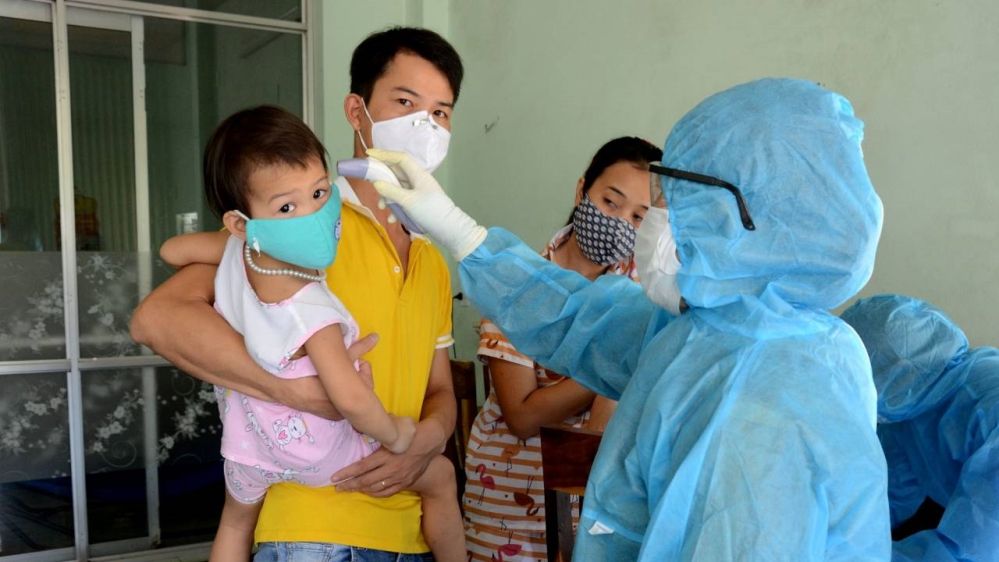 A health worker takes temperatures of residents at the area of a newly found coronavirus infected patient in Da Nang on Sunday