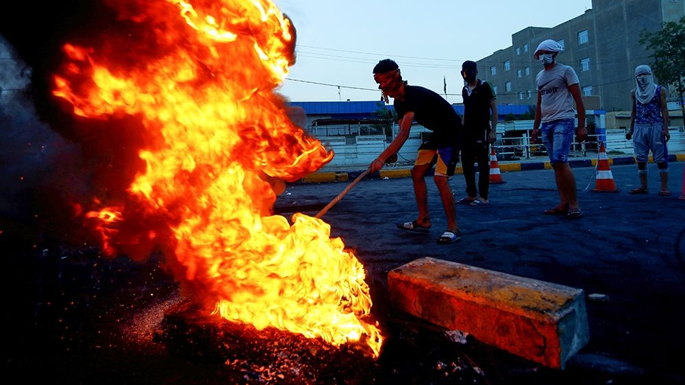Iraqi demonstrators burn tires to block the road during a protest over poor public services in the holy city of Najaf