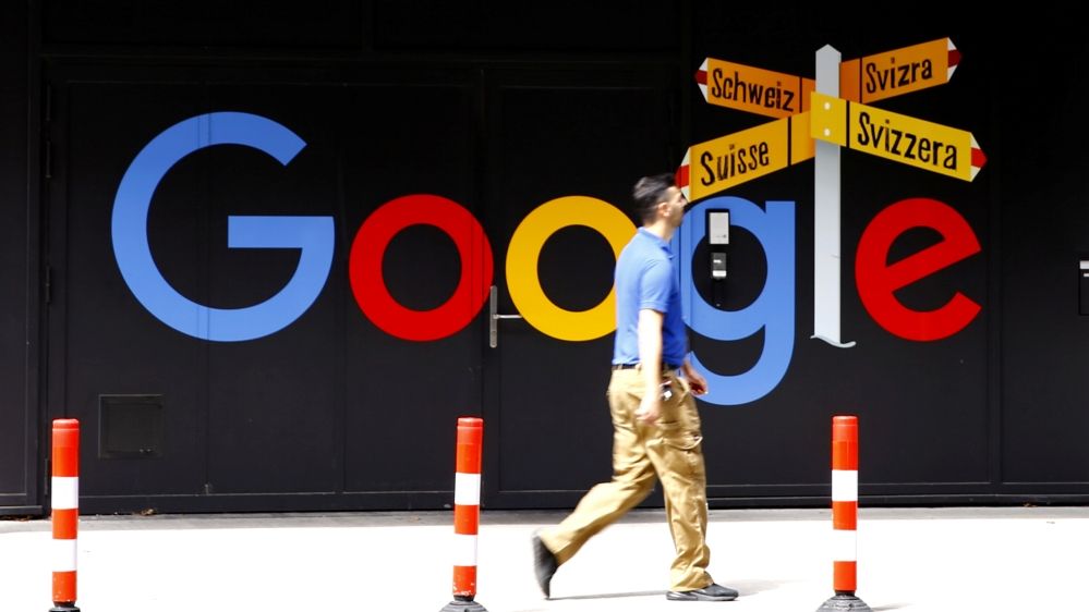 A man walks past a logo of Google in front of at an office building in Zurich, Switzerland