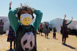 A displaced girl wears a face mask as she takes part in an event organzied by Violet Organization