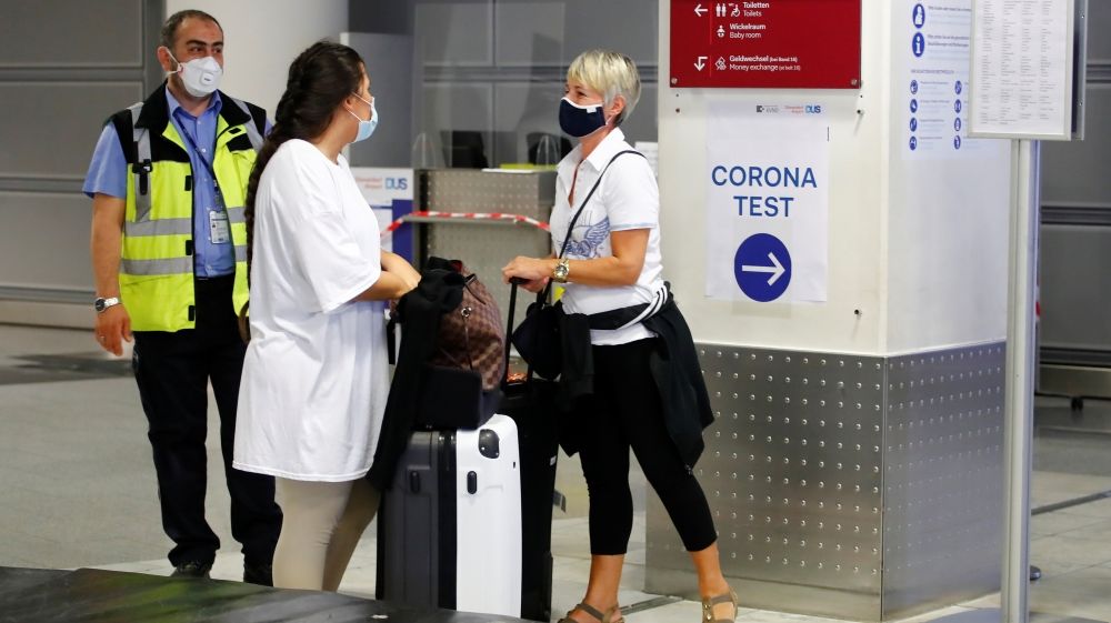 Travellers line up at a new coronavirus testing centre at Dusseldorf Airport in Dusseldorf, Germany