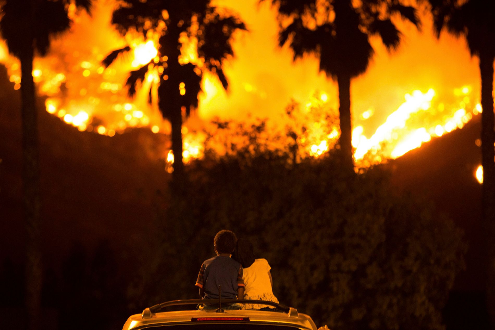 Six-year-old King Bass (left) sits and watches the Holy Fire burn from on top of his parents’ car as his five-year-old sister Princess rests her head on his shoulder on August 9, 2018 in Lake Elsinore, California