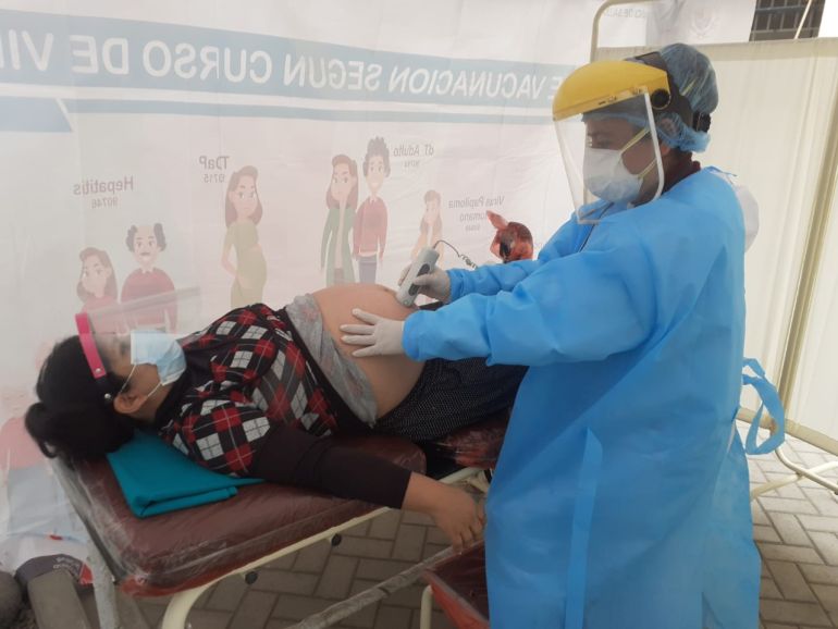 A health worker in Peru does a scan on a pregnant woman during the COVID-19 outbreak