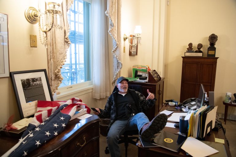 A supporter of US President Donald Trump sits inside the office of US Speaker of the House Nancy Pelosi as he protests inside the US Capitol in Washington, DC