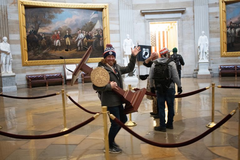 A pro-Trump rioter, identified by the FBI as Adam Johnson, carries the lectern of the speaker of the House, Nancy Pelosi, through the rotunda of the US Capitol building