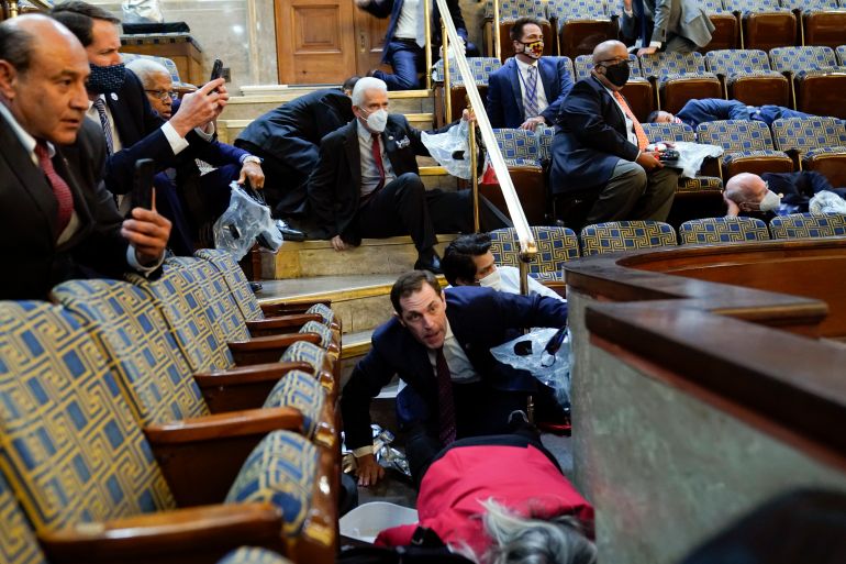 People shelter in the House gallery as protesters try to break into the House Chamber
