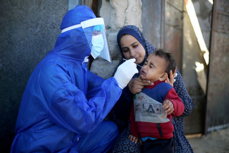 A Palestinian medical worker collects a swab sample from a boy to be tested for the coronavirus disease (COVID-19), in the southern Gaza Strip, January 14, 2021