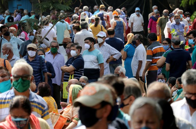 People wearing protective face masks wait to receive COVID-19 vaccine at a vaccination centre in Mumbai