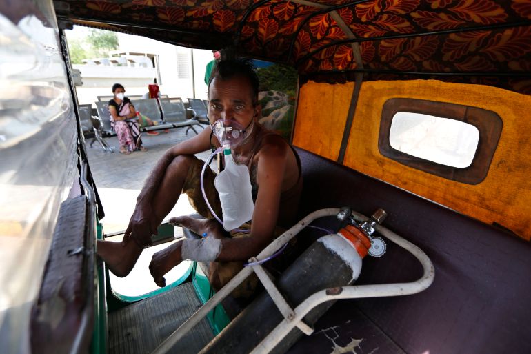 A COVID-19 patient breathes with the help of an oxygen mask as he waits inside an auto rickshaw to be admitted to a dedicated COVID-19 government hospital in Ahmedabad, India