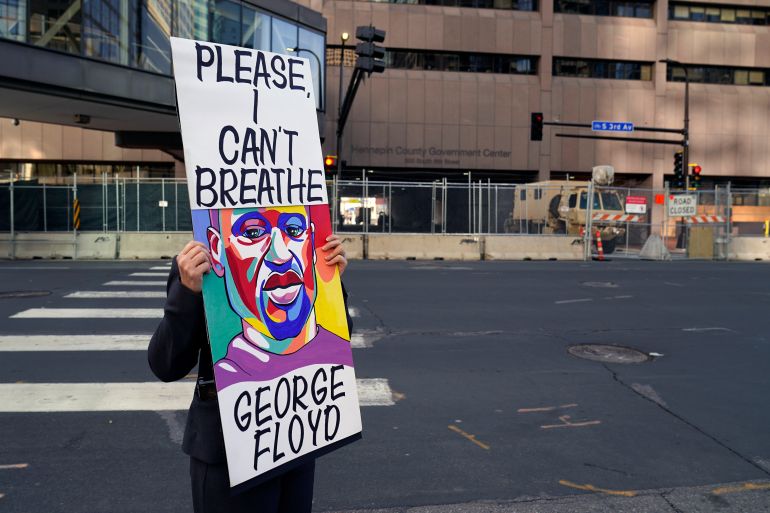 A protester holds a sign across the street from the Hennepin County Government Center where the trial of former Minneapolis police officer Derek Chauvin is in its second week