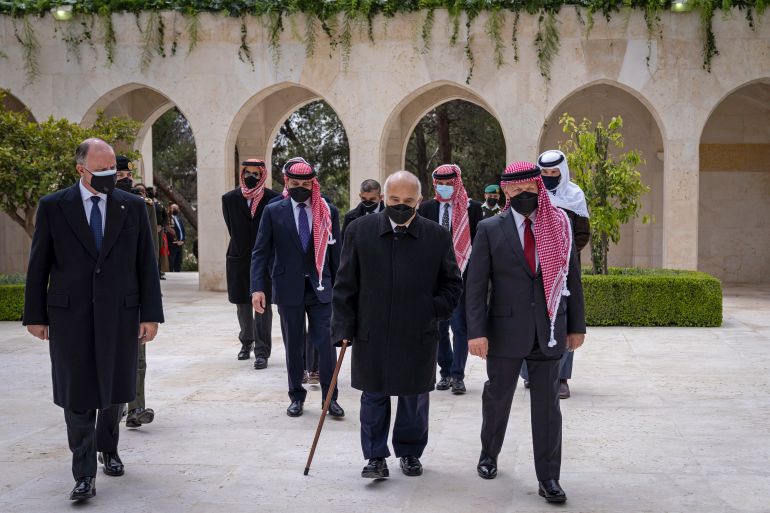 Jordan’s King Abdullah II, second right, Prince Hamzah bin Al Hussein, fourth right in blue mask, Prince Hassan bin Talal, fifth right, and others arriving to visit the tombs of former kings in Amman [File: Royal Court Twitter Account via AP]