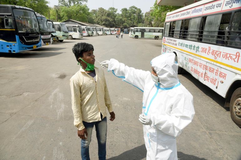 A health worker collects swab sample from a passenger at a government bus stand near Gandhi Maidan, amid the coronavirus pandemic, on April 12, 2021 in Patna, India