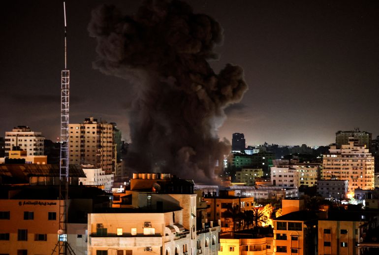 A plume of smoke rises above buildings in Gaza City as Israeli warplanes target the Palestinian enclave, early on May 17, 2021 [Mahmud Hams/AFP].