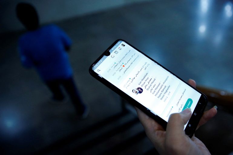 Iranian man checking the Clubhouse App on his smartphone
