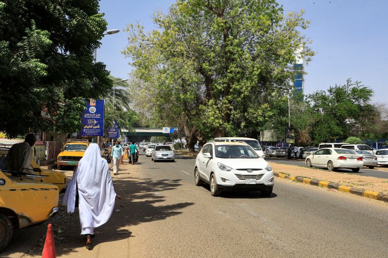 Cars drive past pedestrians walking along Nile Street adjacent to the Blue Nile in