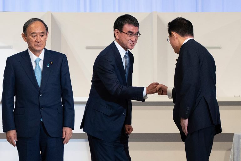 Taro Kono, center, fist bumps with Fumio Kishida after Kishida was announced the winner of the LDP leadership election in Tokyo