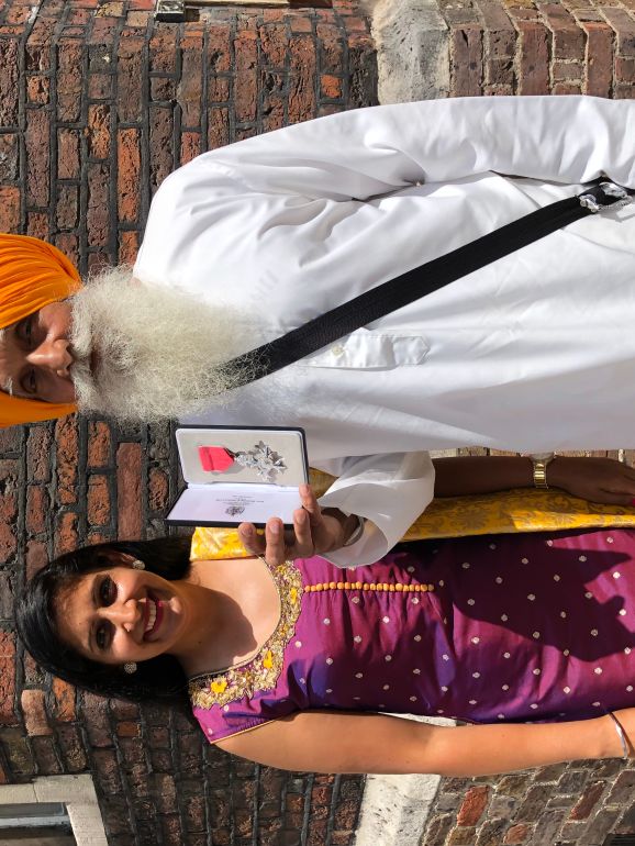 The writer with her father after he received his MBE [Photo courtesy of Minreet Kaur]