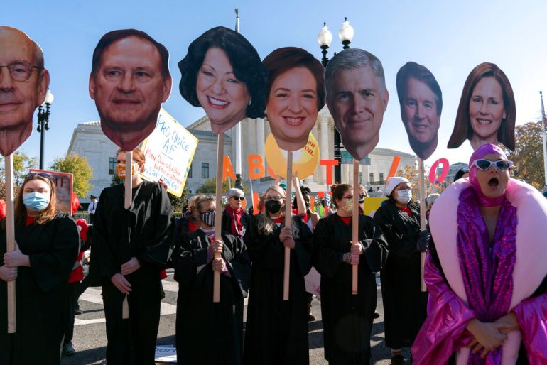 Abortion rights advocates held cardboard cutouts of Supreme Court justices as the court heard arguments on a 2018 Mississippi law that bans abortions after 15 weeks of pregnancy