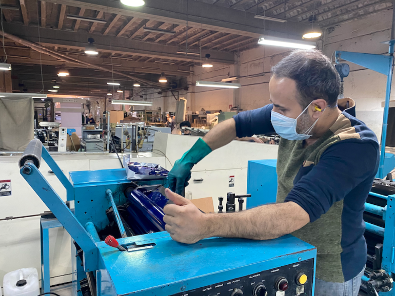 A man works at an industrial machine in a factory.