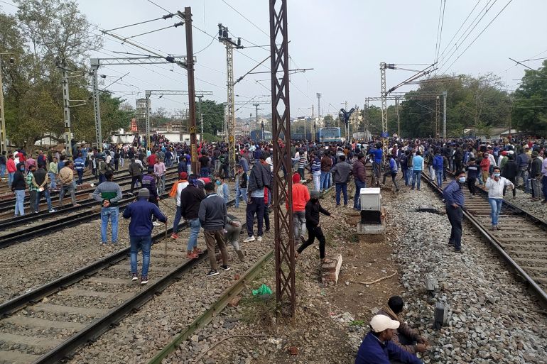 People gather near a train set on fire by angry mobs in protests over access to railway jobs, in Gaya [AFP]