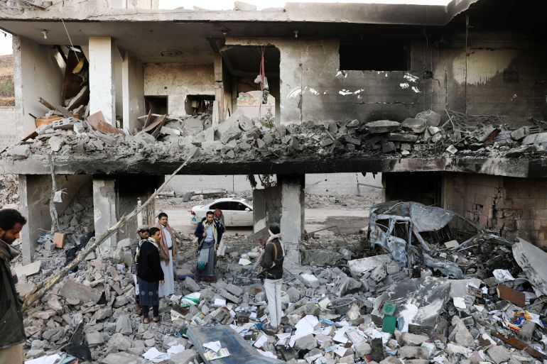 Guards stand on the rubble of a house hit by Saudi-led air raids in Sanaa, Yemen, January 18, 2022