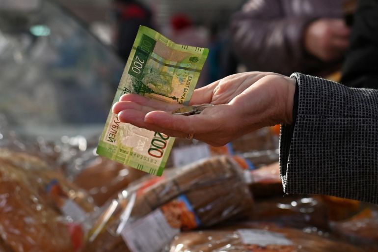 A customer is seen handing over Russian rouble banknotes and coins to a vendor at a market in Omsk, Russia