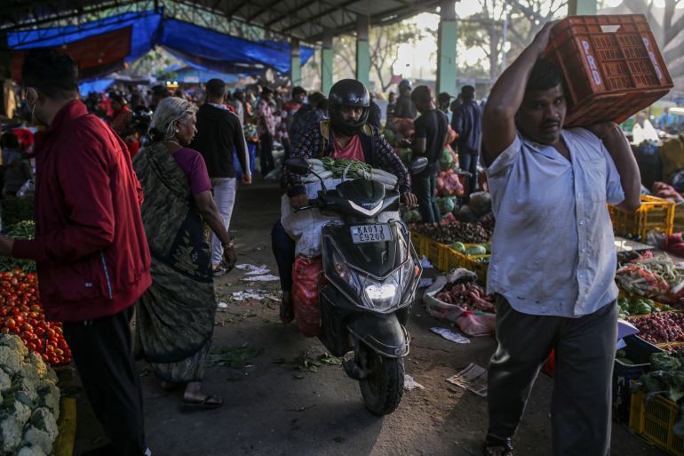 Customers buy vegetables at a wholesale market in Bengaluru, India