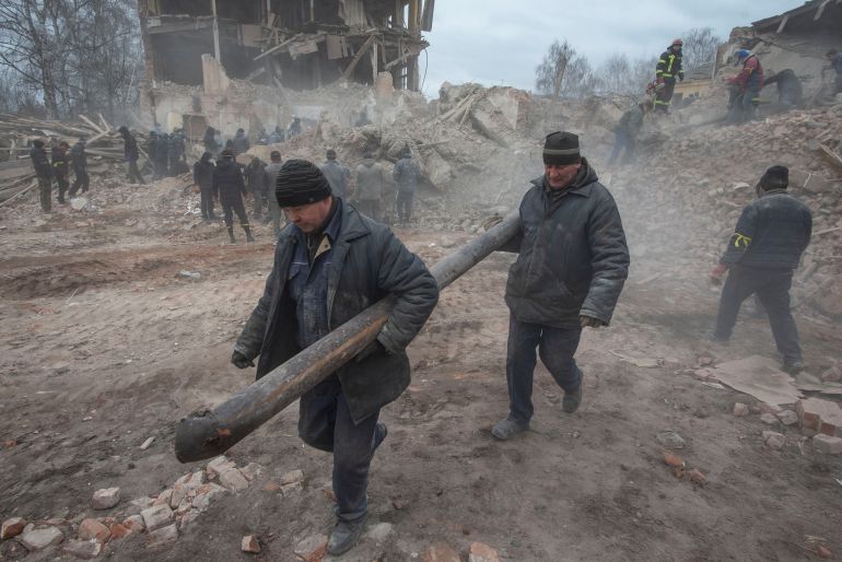 People remove debris at the site of a military base building in the Sumy region