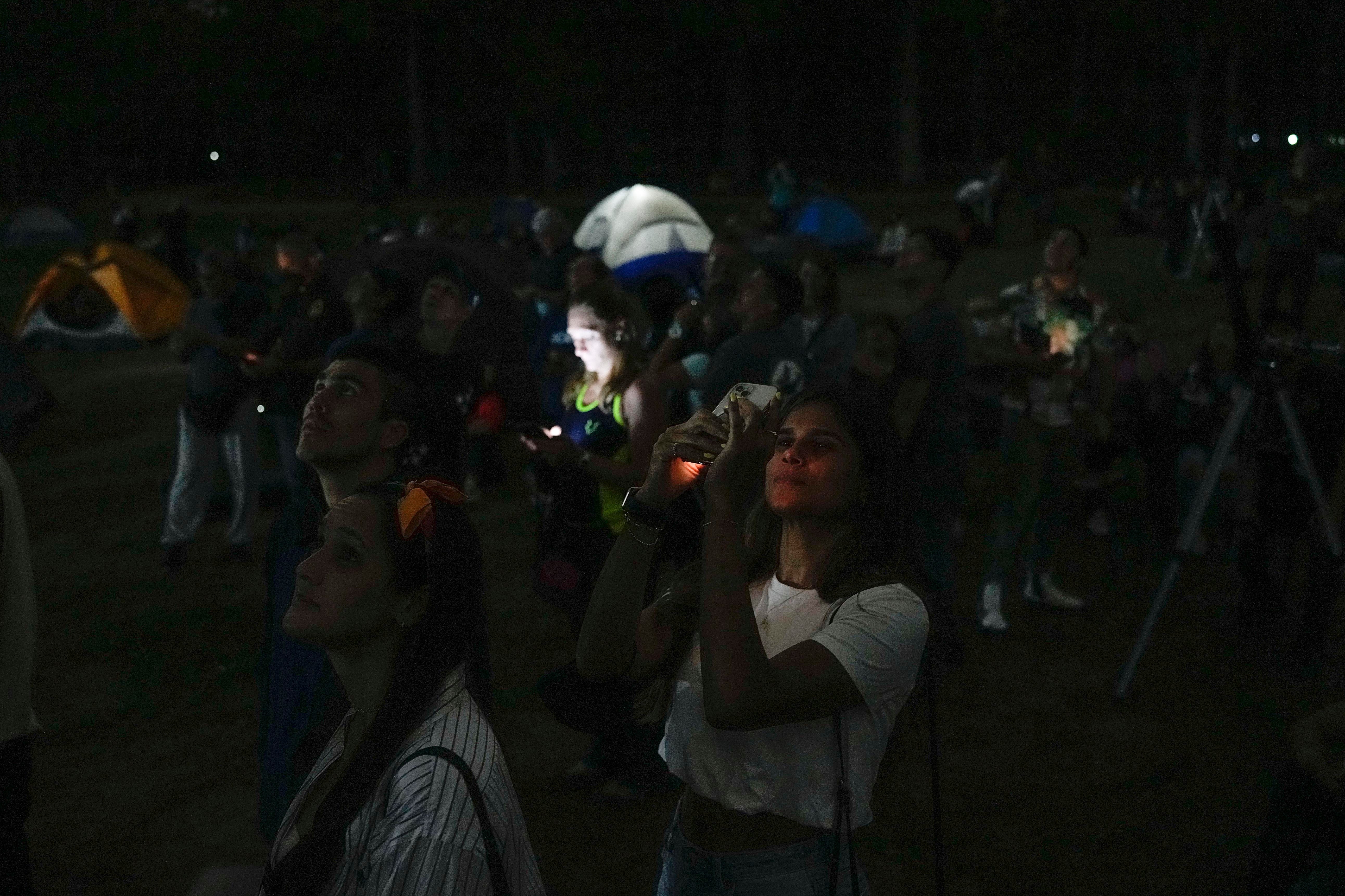 A woman takes a photo of the moon with her cellphone during the first blood moon of the year, in Caracas, Venezuela