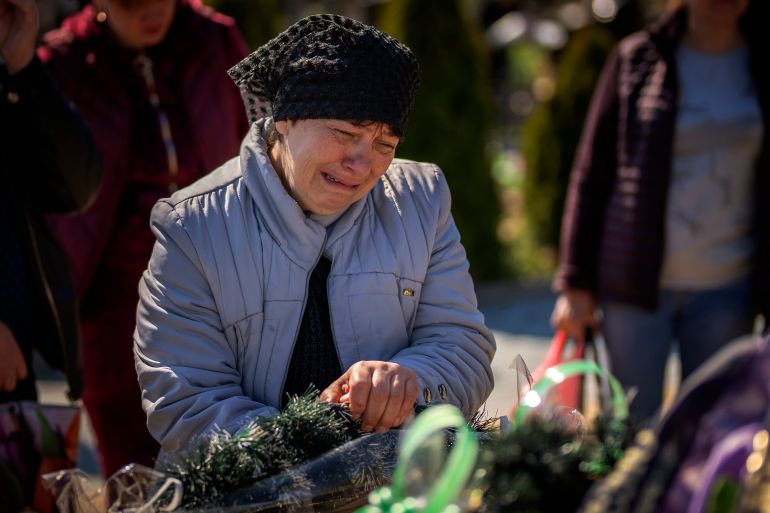 The mother of Oleksandr Mozheiko, 31, an Irpin Territorial Defence soldier killed by the Russian army, cries at his grave at the cemetery of Irpin, on the outskirts of Kyiv on May 1, 2022