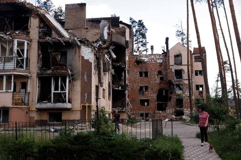 Resident Lyudmila, who lives in a destroyed apartment block, walks her dog near her home in Irpin, outside Kyiv, as Russia's attacks on Ukraine continues