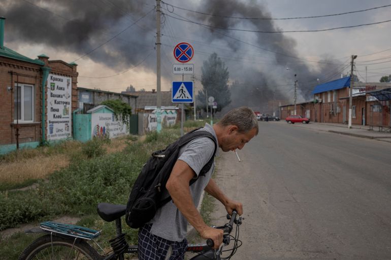 A man pushes a bicycle across a street in front of the market after shelling, in Sloviansk, Donetsk region, Ukraine, July 5, 2022