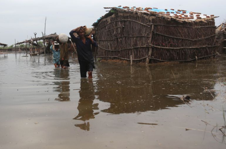 People wade through a flooded area following heavy rains in Sanghar, Pakistan