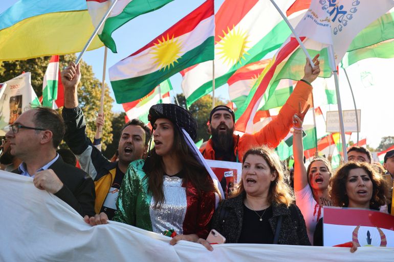 Demonstrators hold a banner and flags during a protest following the death of Mahsa Amini in Iran, in Berlin.
