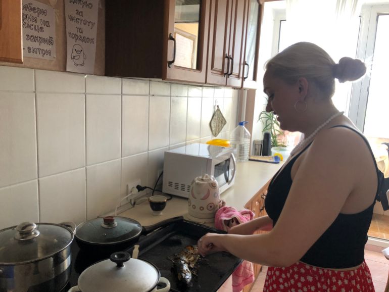 A photo of Mira cutting a fish in the kitchen.