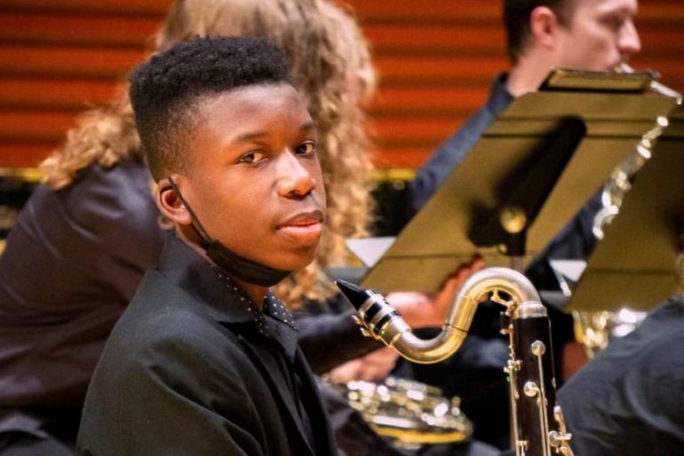 A young boy poses with a bass clarinet