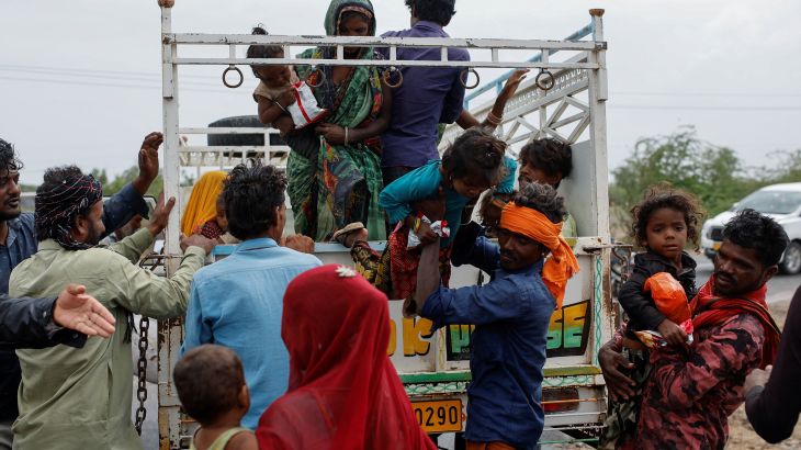 A man carries a child from a truck during an evacuation before the arrival of cyclone Biparjoy in Jakhau in the western state of Gujarat, India, June 14, 2023.