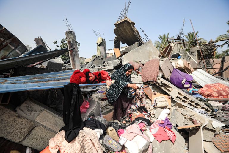 Sabah Abu Khater, 60, collects belongings for her family from the rubble of her bombed house in Beit Hanoun